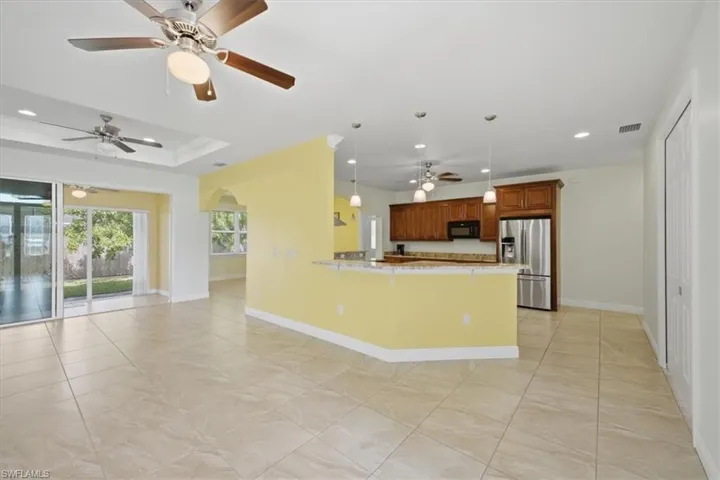 Open-concept living area with large format tile flooring, a tray ceiling, and sliding glass doors