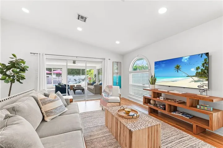 Living room with recessed lighting, light wood-style flooring, and vaulted ceiling
