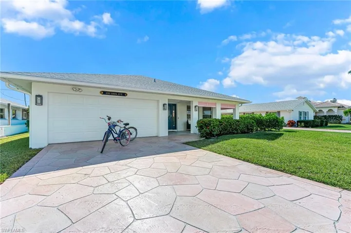Single story home with a front lawn, concrete driveway, stucco siding, and an attached garage