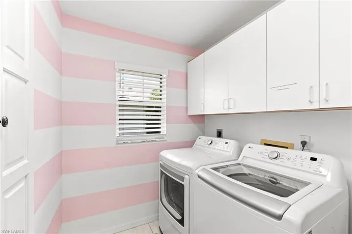 Laundry area featuring washing machine and dryer, cabinet space, and light tile patterned floors