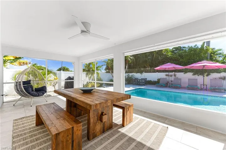 View of swimming pool featuring a fenced backyard, outdoor dining space, ceiling fan, a patio area, and a sunroom
