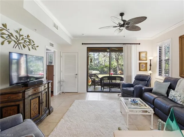 Living area with crown molding, a ceiling fan, healthy amount of natural light, and light tile patterned floors