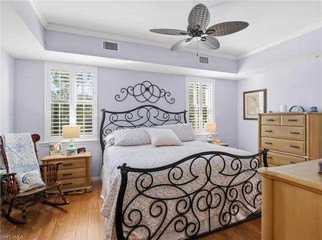 Bedroom with ornamental molding, dark wood finished floors, and ceiling fan