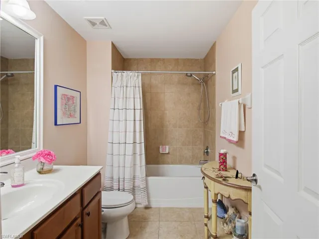 Bathroom with vanity, shower / bath combo, and light tile patterned flooring