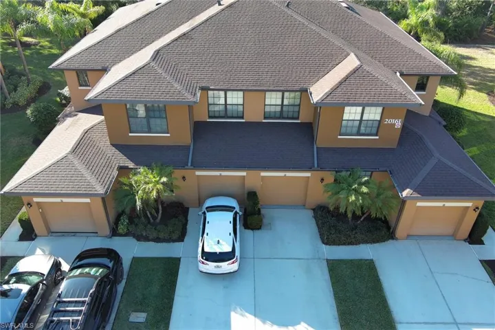 View of front facade featuring stucco siding, driveway, an attached garage, and roof with shingles