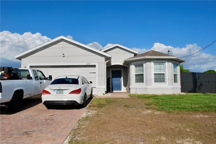 Ranch-style home featuring decorative driveway, a garage, and stucco siding