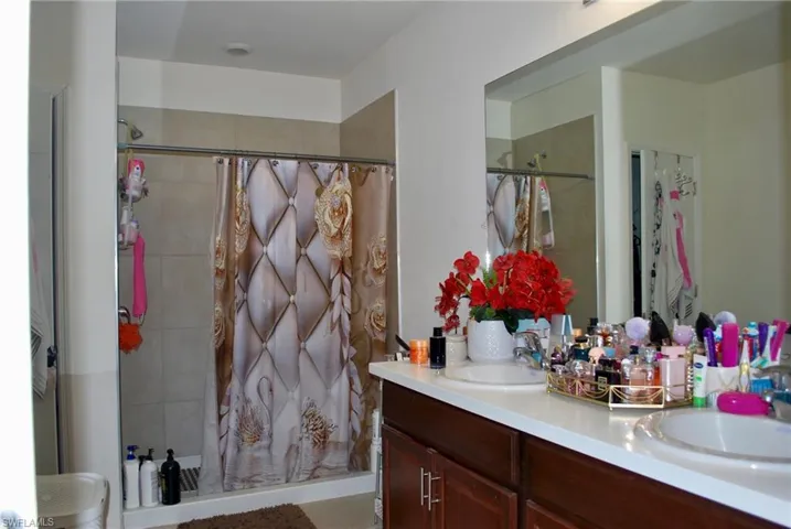 Full bath featuring double vanity and a tile shower