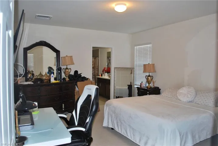 Bedroom featuring light colored carpet, ensuite bath, and an office area
