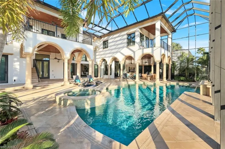 Patio area, a pool with connected hot tub, two balconies, and spiral staircase