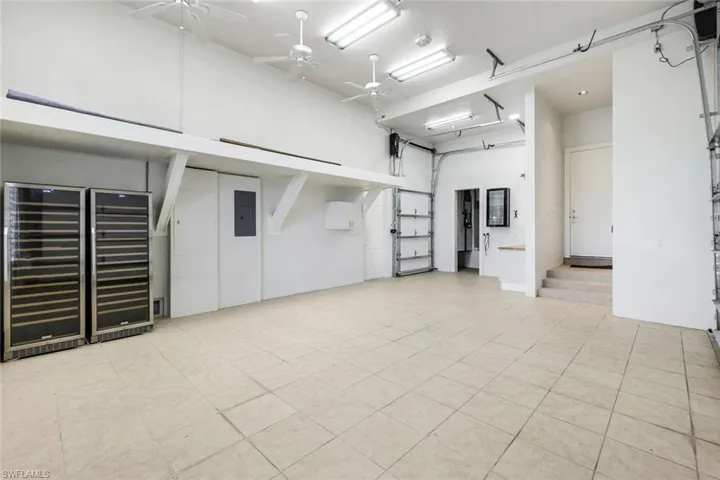 High ceiling, a garage, beverage cooler, a ceiling fan, and electric panel