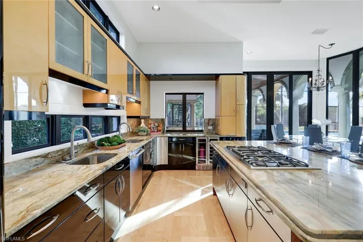 Kitchen featuring light stone countertops, glass insert cabinets, recessed lighting, appliances with stainless steel finishes, and a chandelier
