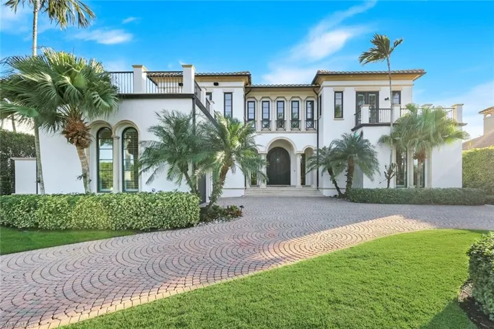 Mediterranean / spanish house with curved driveway, stucco siding, and a balcony