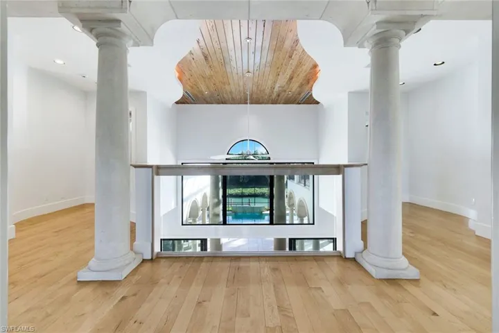 Upstairs hallway featuring decorative columns, wooden ceiling, recessed lighting