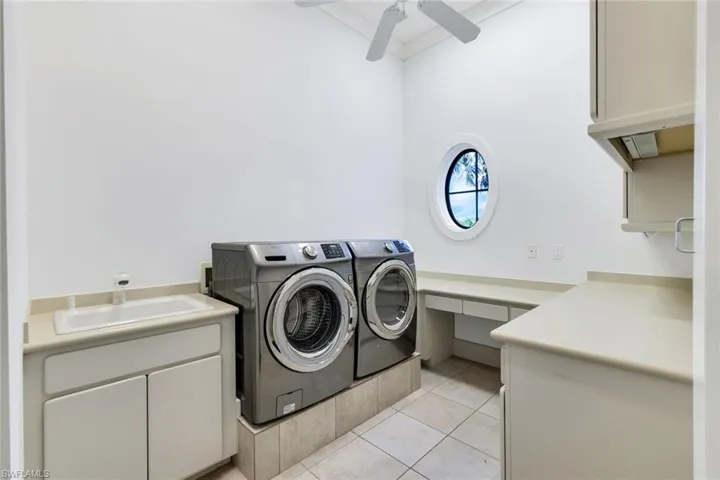 Laundry room with independent washer and dryer, cabinet space, and ceiling fan