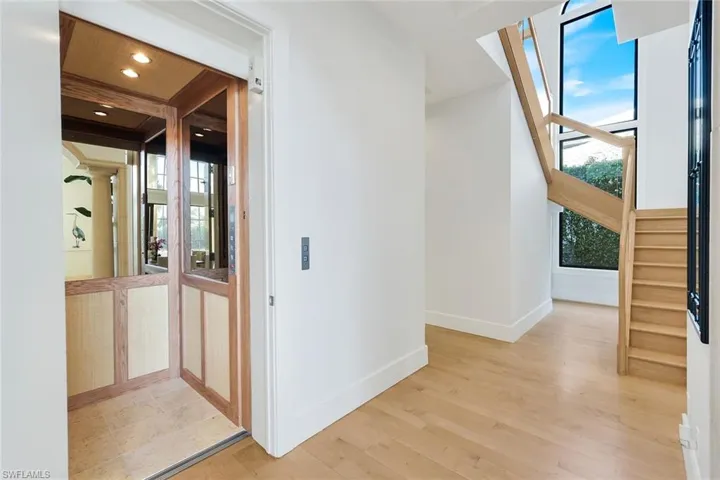 Corridor with elevator, stairway, and light wood  floors