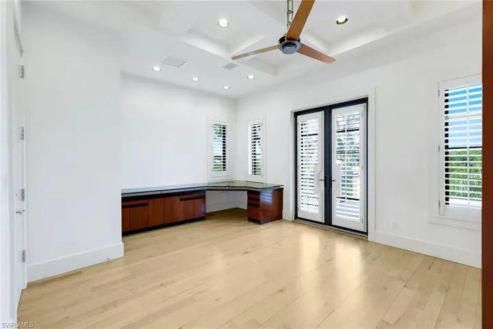 Unfurnished office with built in desk, coffered ceiling, recessed lighting, and beam ceiling