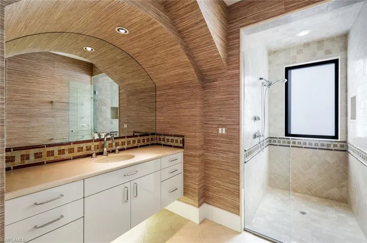 Bathroom featuring vanity, a walk in shower, tasteful backsplash, and recessed lighting