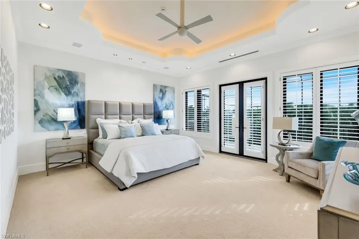 Primary bedroom featuring recessed lighting, ceiling fan, crown molding, access to exterior, and a raised ceiling