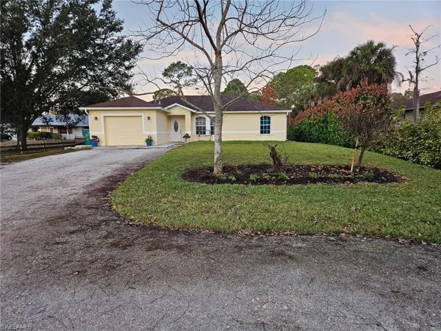 Single story home with driveway, stucco siding, a garage, and a yard