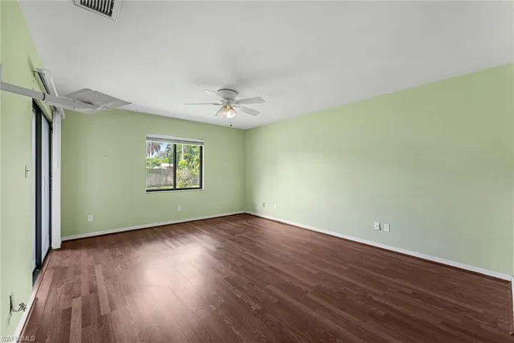 Empty room with ceiling fan and dark wood-type flooring