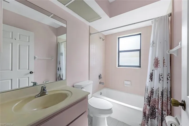 Full bathroom with tile patterned floors, vanity, toilet, and shower / bath combination with curtain