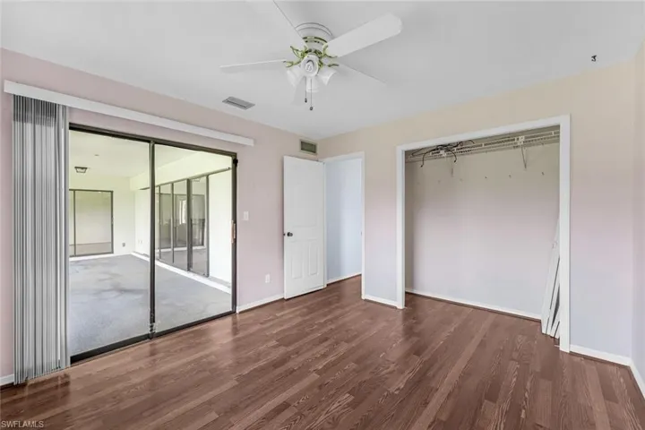 Unfurnished bedroom featuring access to exterior, ceiling fan, hardwood / wood-style flooring, and a closet