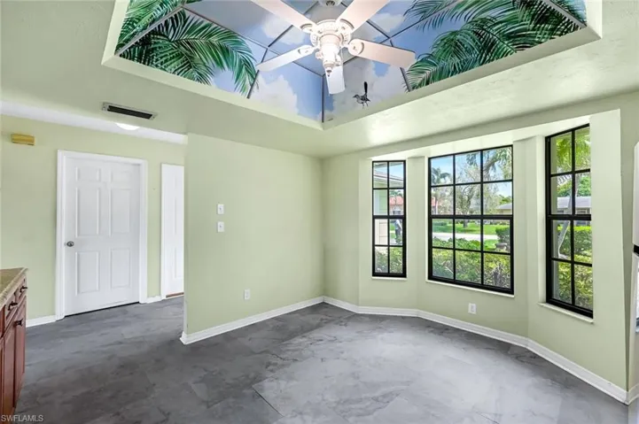 Empty room featuring ceiling fan, a raised ceiling, and dark tile patterned floors