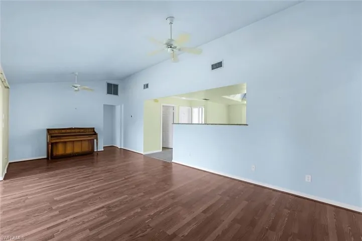 Unfurnished living room featuring wood-type flooring, high vaulted ceiling, and ceiling fan