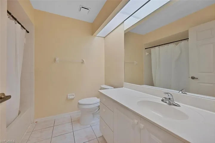 Full bathroom with vanity, shower / tub combo with curtain, toilet, and tile patterned floors