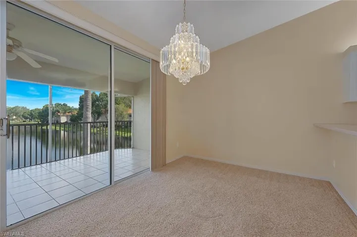 Unfurnished room with carpet floors, ceiling fan with notable chandelier, and a water view