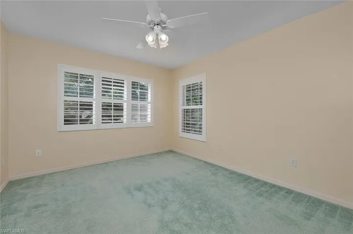Carpeted spare room featuring ceiling fan