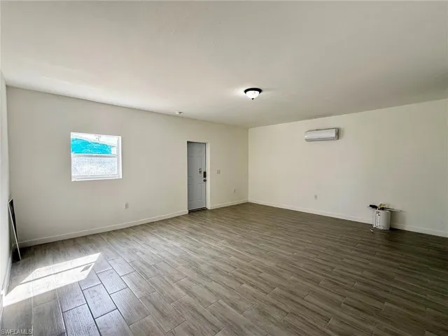 Unfurnished guest room featuring tile finish floors and a wall unit AC