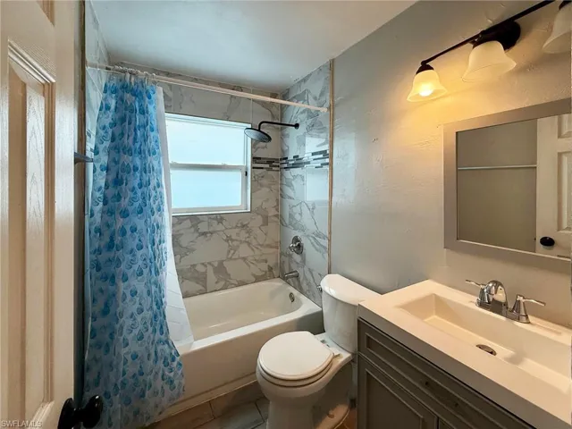 Bathroom with shower / bath combo with shower curtain and vanity