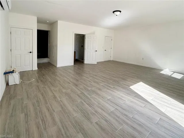 Unfurnished guest room with tile finish floors and an AC wall unit
