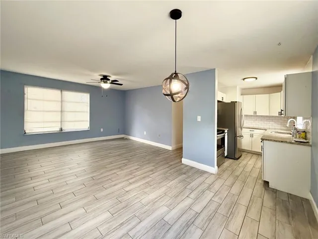 Kitchen featuring white cabinets, open floor plan, decorative light fixtures, ceiling fan, and wood tiled floors