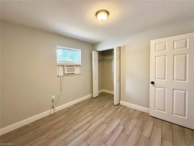 Unfurnished bedroom featuring a closet, wood finish floors, and cooling unit