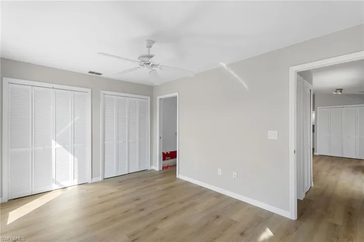 Unfurnished Guest bedroom with two closets, light wood-style floors, and private bath entrance.