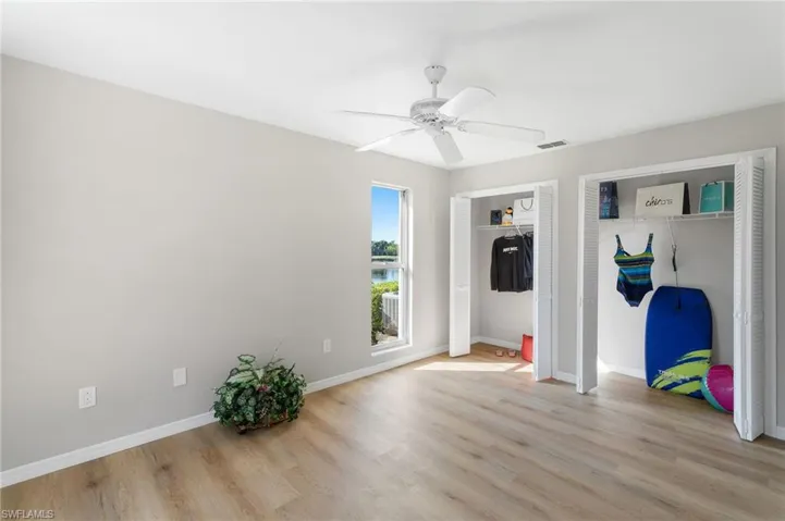 Unfurnished Guest bedroom with ceiling fan, wood-like  finished floors, multiple closets, and baseboards