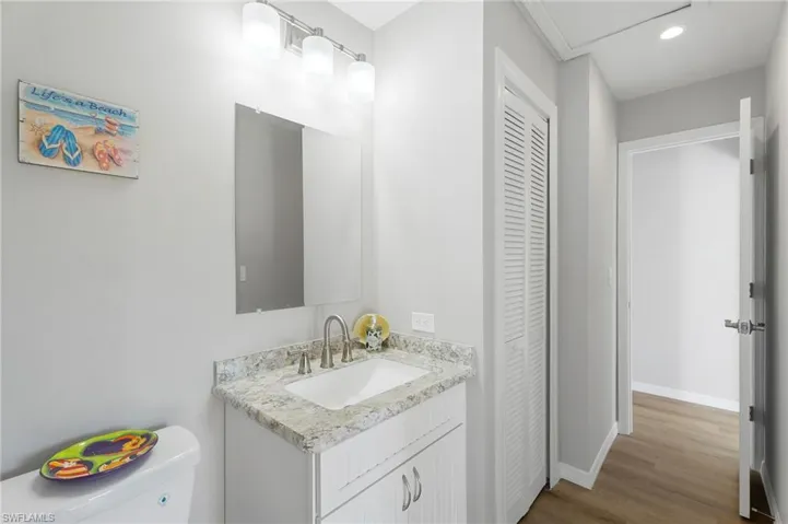 Guest Bathroom featuring a closet, toilet, linen closet, vanity, and wood-like  finished floors.