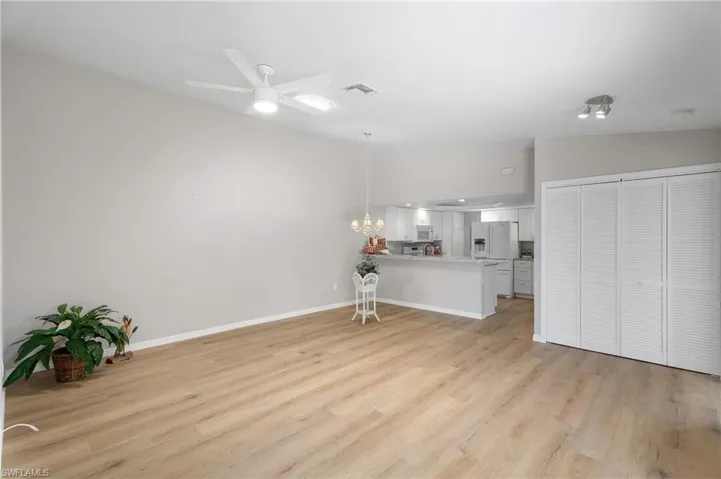 Unfurnished living room featuring light wood-style floors, ceiling fan, and lofted ceiling.