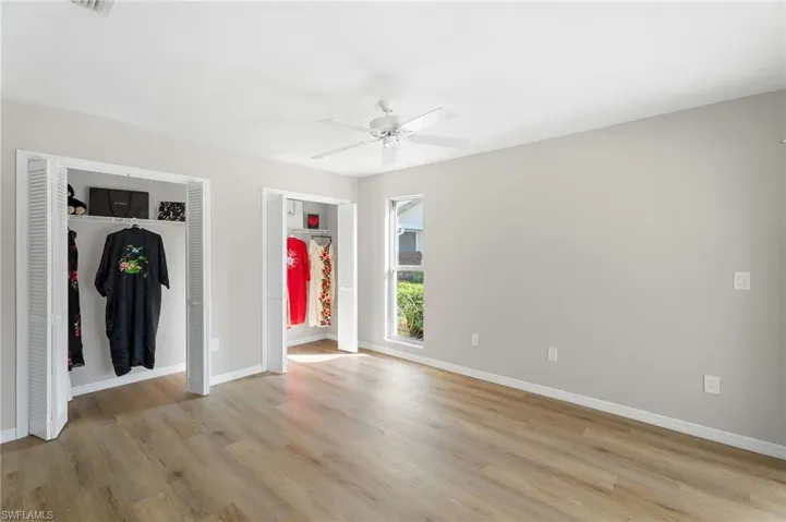 Unfurnished primary bedroom with multiple closets, baseboards, and light wood-type flooring