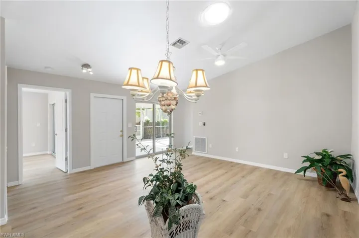 Dining space with custom chandelier, and light wood-style flooring.