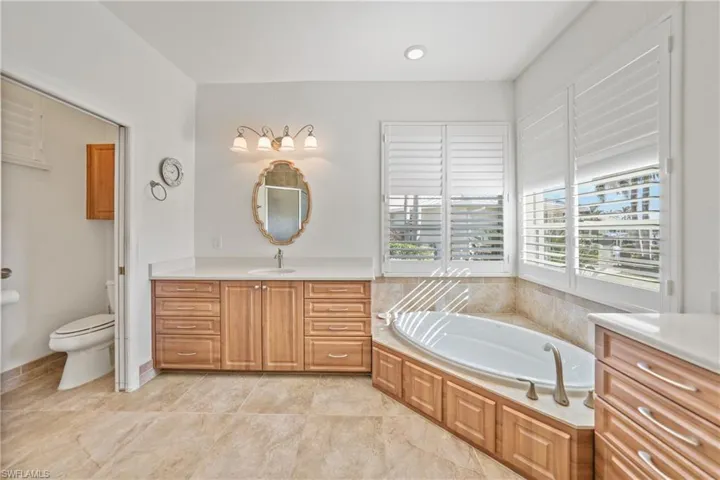 Bathroom with vanity, toilet, and a tub to relax in