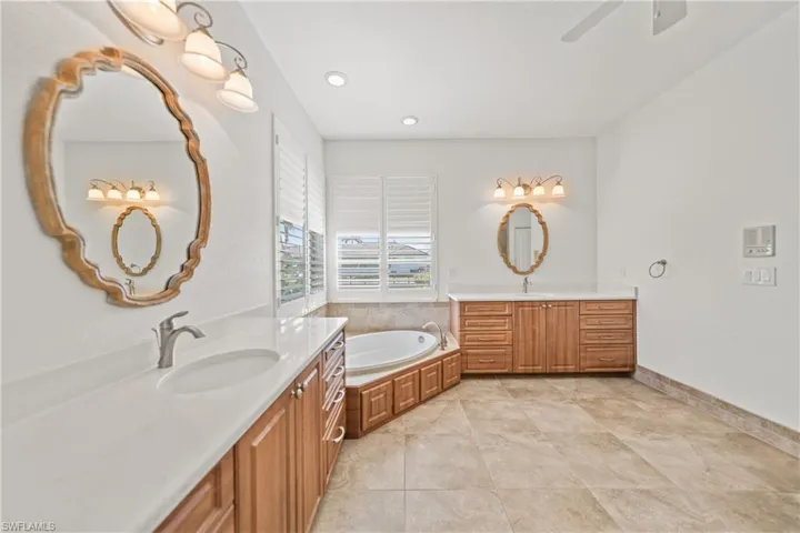 Bathroom with a tub, ceiling fan, tile patterned flooring, and vanity