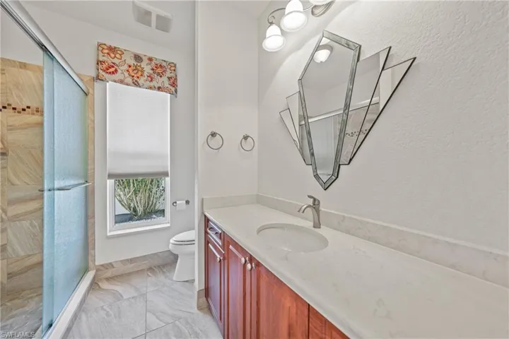 Bathroom with vanity, an enclosed shower, and toilet