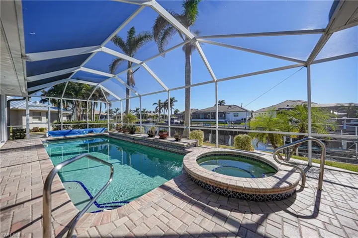 View of swimming pool with a patio, a lanai, an in ground hot tub, and a water view