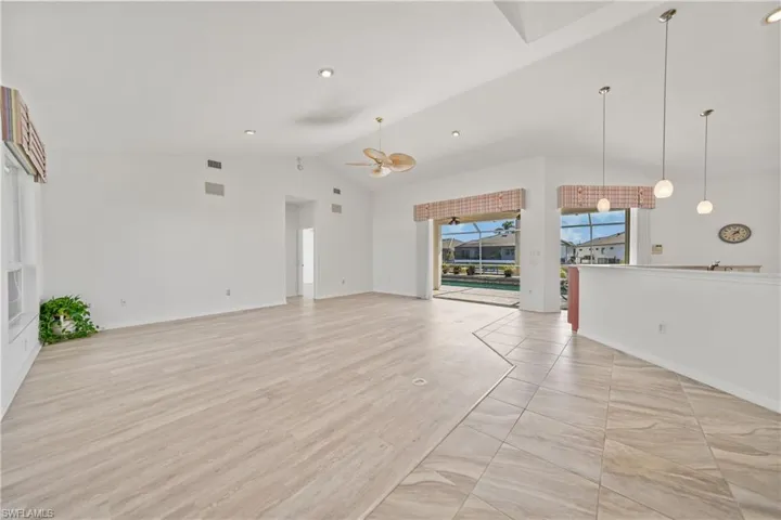 Unfurnished living room featuring ceiling fan, light hardwood / wood-style floors, and vaulted ceiling