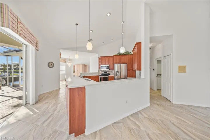 Kitchen featuring sink, stainless steel appliances, high vaulted ceiling, kitchen peninsula, and pendant lighting