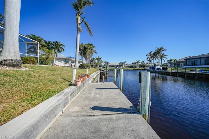 Dock area featuring glass enclosure, a yard, and a water view