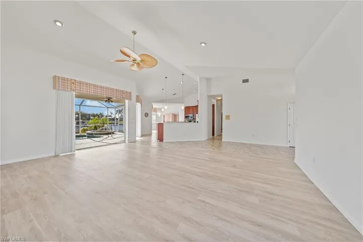 Unfurnished living room with light wood-type flooring, high vaulted ceiling, and ceiling fan